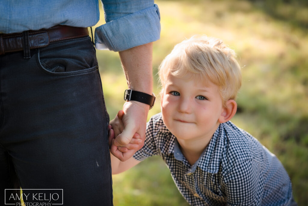 Young boy holding father's hand at Lincoln Park in West Seattle