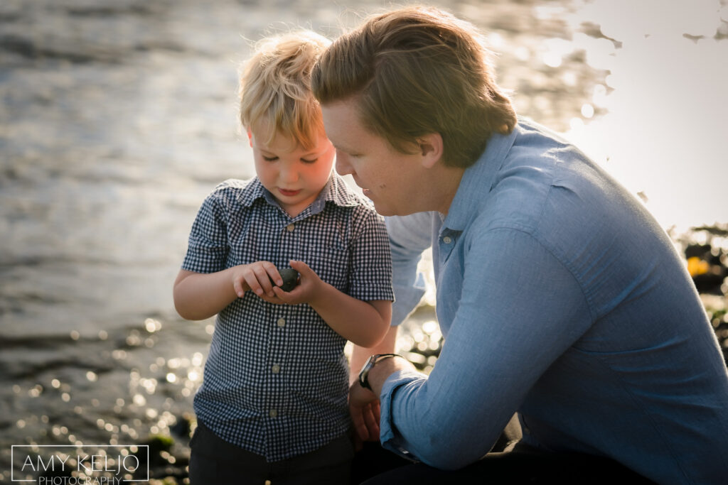 Father and son looking at a rock on the beach at Lincoln Park in West Seattle