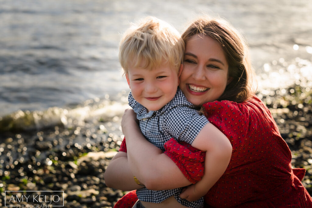 Mother hugging son on beach at Lincoln Park in West Seattle