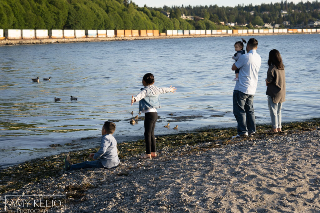 Young family watching train go by on beach at Carkeek Park in Seattle