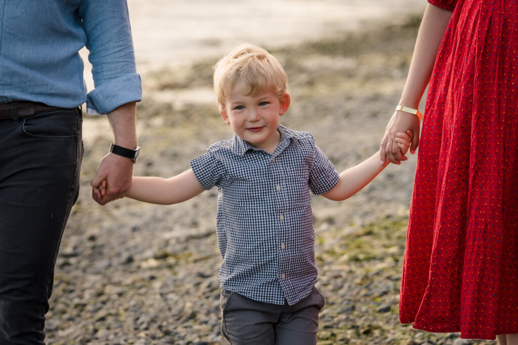 Young boy holding parents hands at Lincoln Park in West Seattle