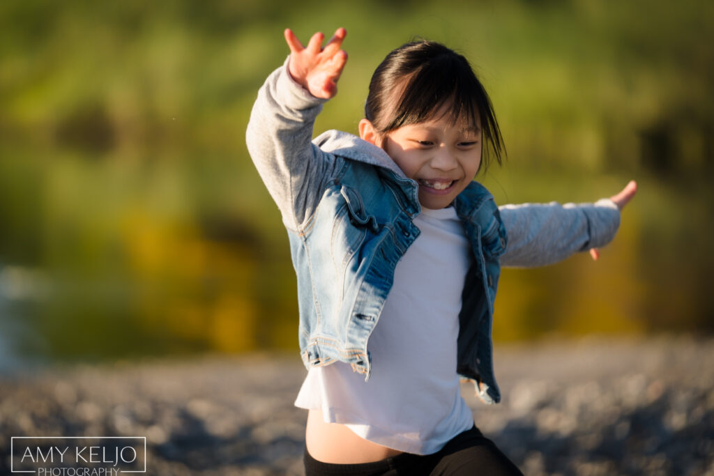 Young girl jumping on beach at Carkeek Park in Seattle