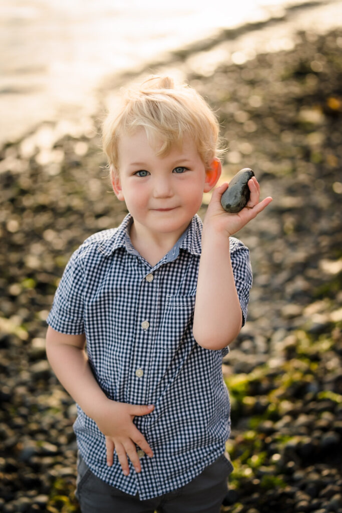 Young boy holding rock on Lincoln Park Beach in Seattle