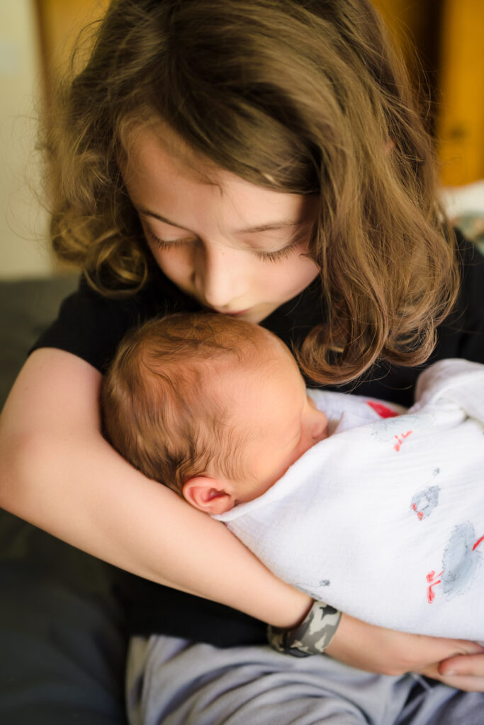 Little boy kissing baby brother at newborn photo shoot