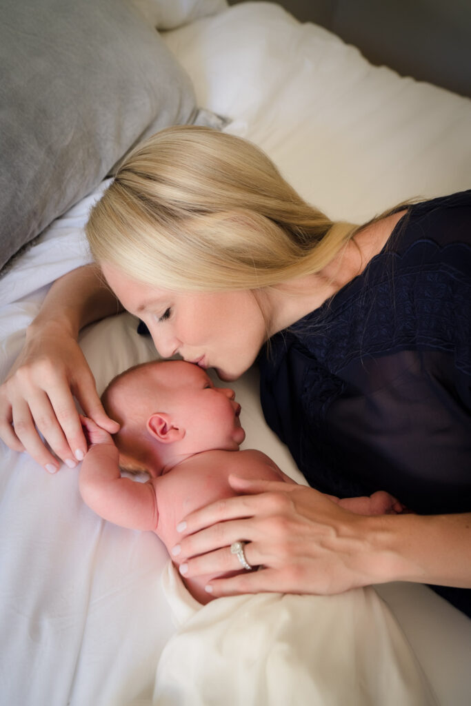 Mother kissing baby at newborn photo shoot