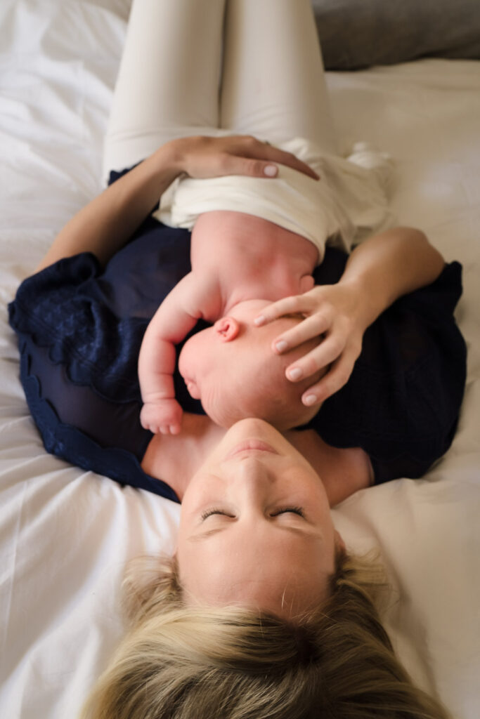 Mother and baby lying on bed at newborn photo shoot