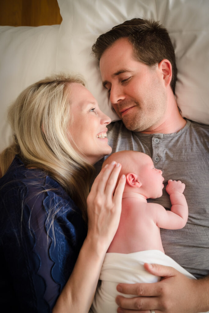 Mother and baby lying on dad's chest at newborn photo shoot