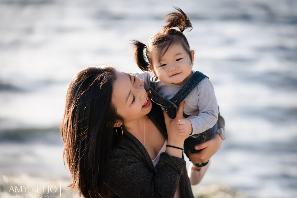 Mother playing with baby daughter on beach at Carkeek Park in Seattle