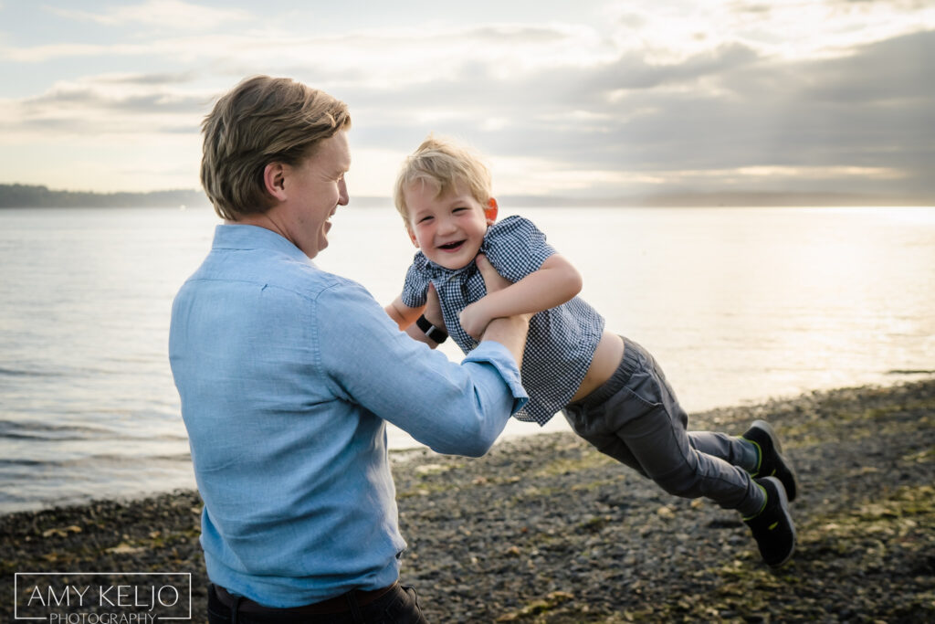 Father spinning son around on beach at Lincoln Park in West Seattle