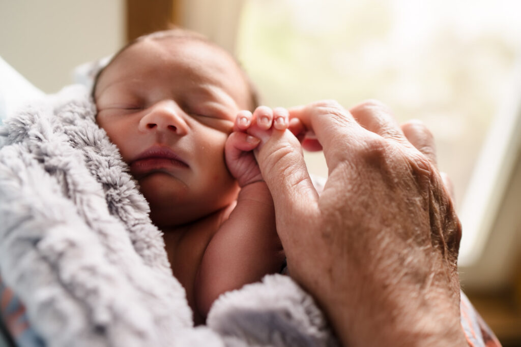 Grandmother holding newborn baby's hand