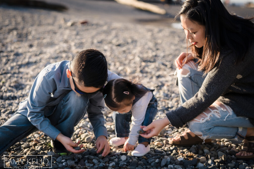 Mother, daughter and son looking at rocks on beach at Carkeek Park in Seattle