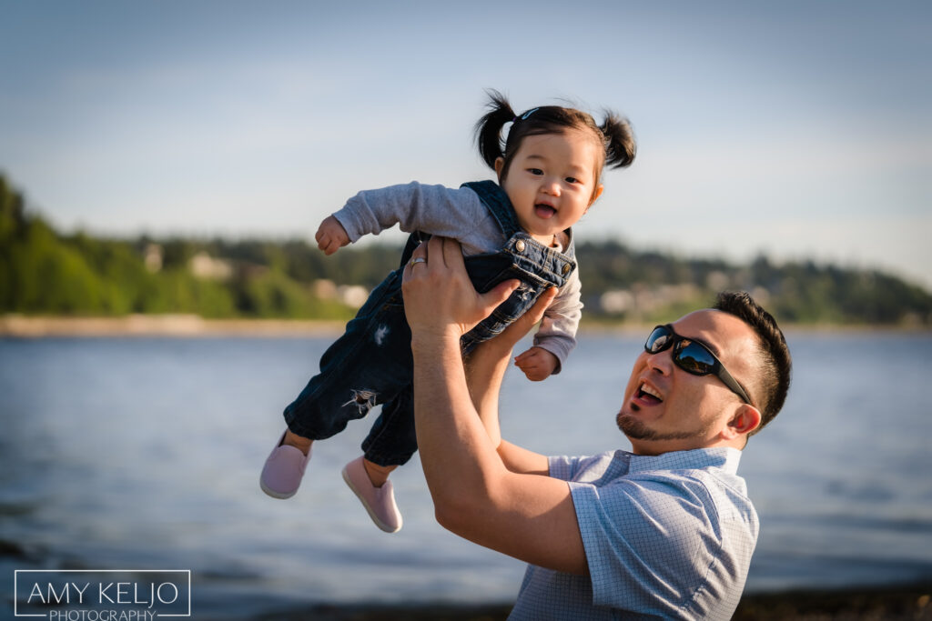 Father throwing his baby daughter up in the air on beach at Carkeek Park in Seattle