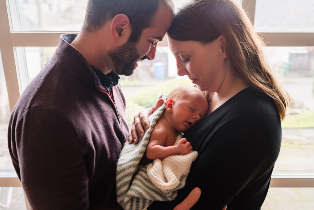 Parents snuggling their newborn at a home photoshoot in Seattle