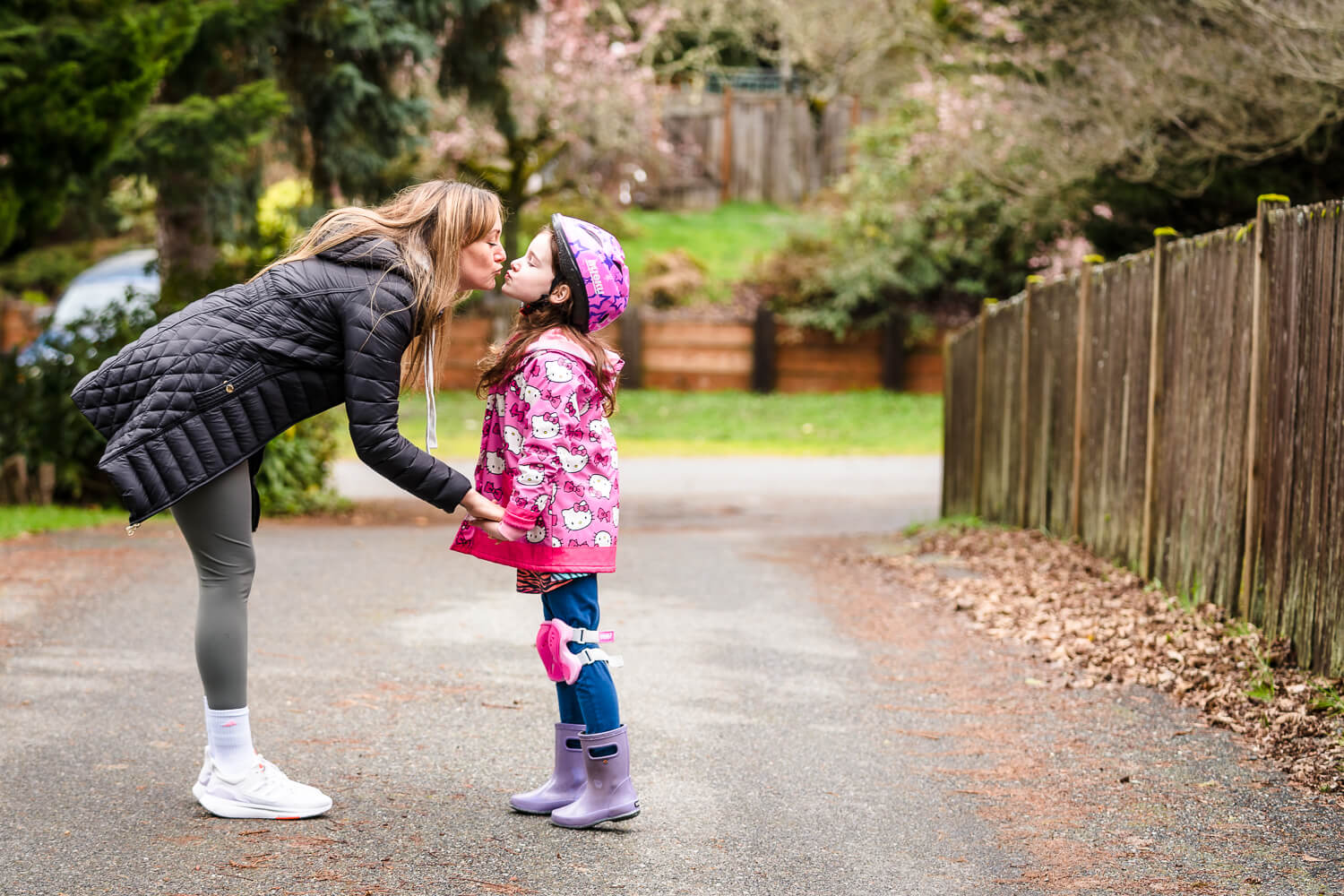 Girl and her mother kiss standing in the driveway