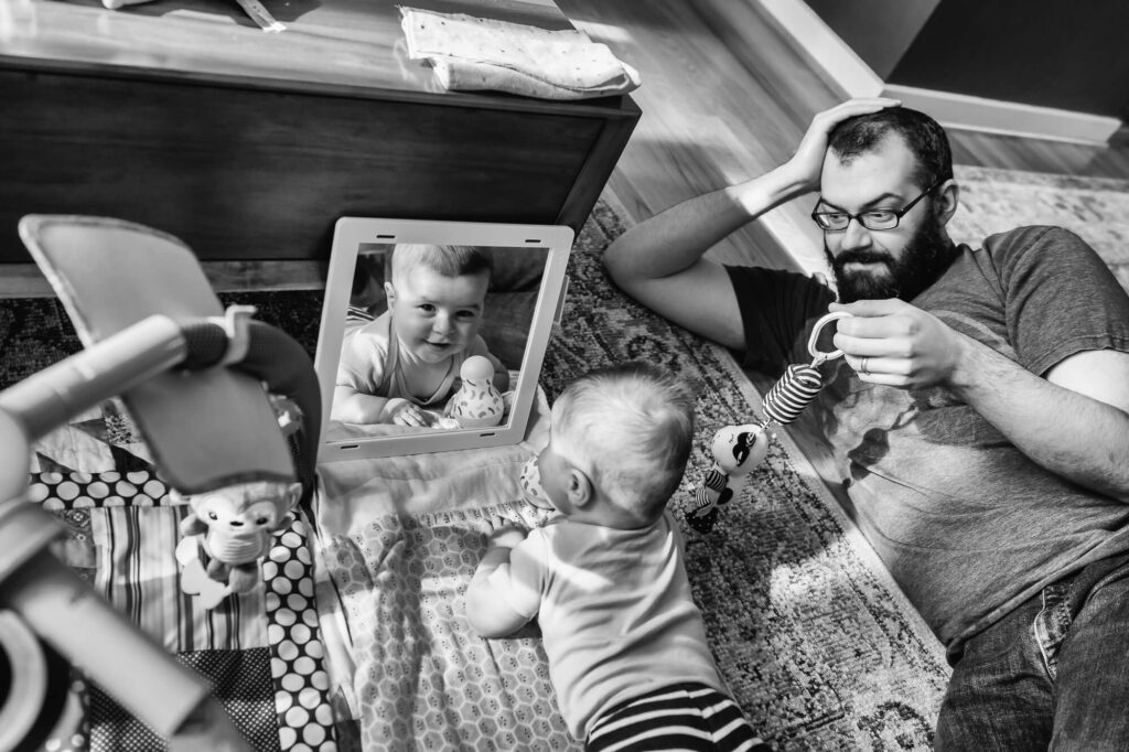Documentary family photography of father playing with infant on living room floor