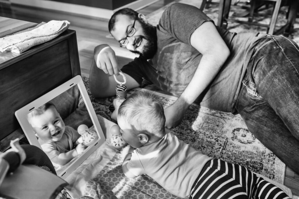 Documentary family photography of father playing with infant on living room floor
